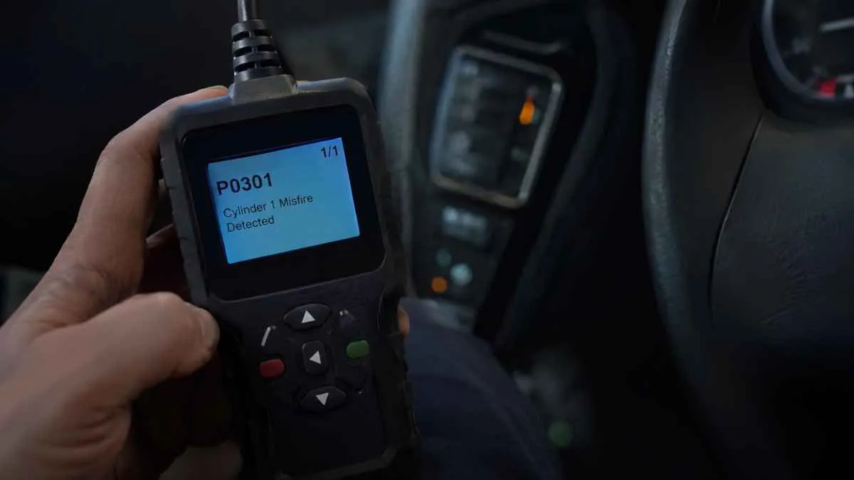 Handheld OBD2 scanner displaying a diagnostic trouble code inside a car